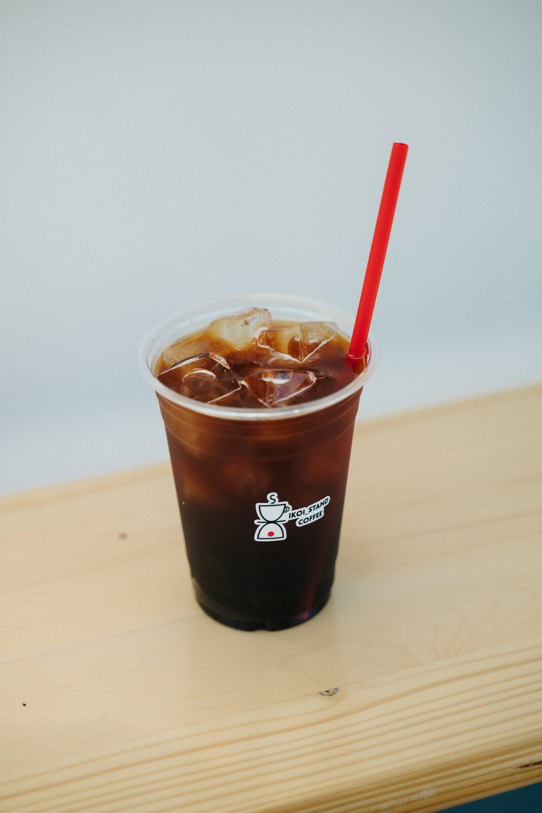 木のカウンターに置かれた、いこいスタンドのアイスコーヒー