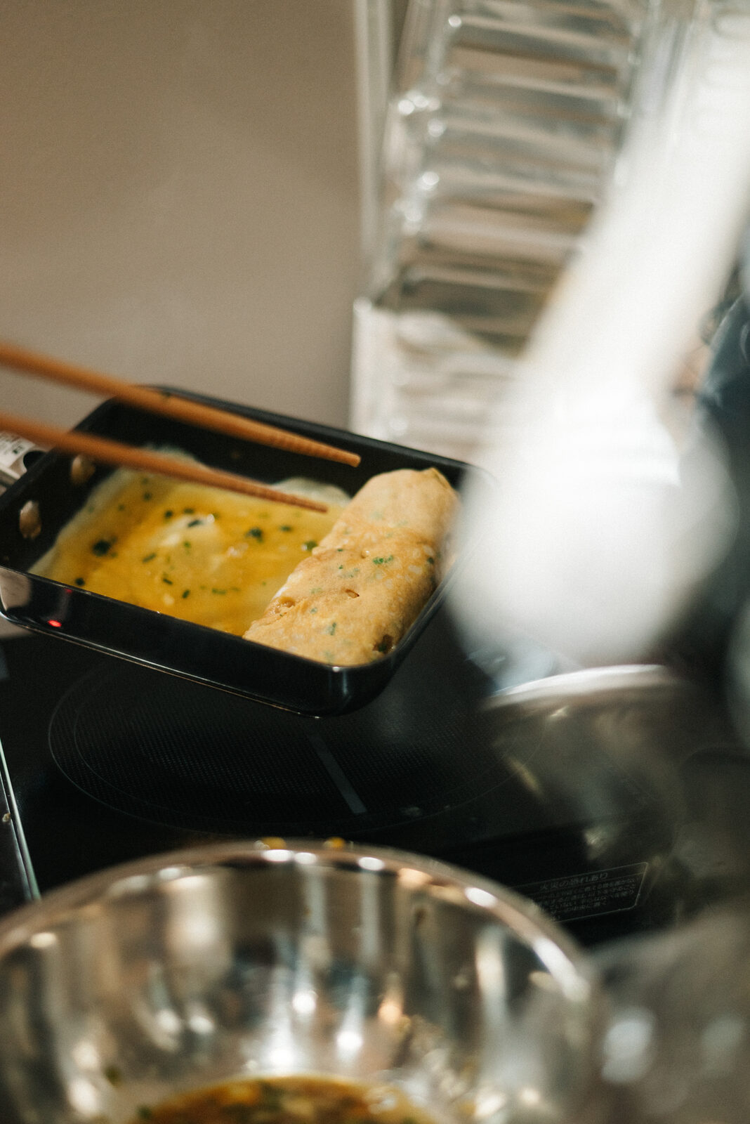 いこいスタンドのキッチンで、卵焼き器で卵焼きを巻いているところ